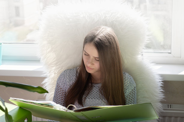 组织家庭办公，远程工作装置。一个年轻的女孩坐在一张桌子旁，在电脑上打字，分析文件，微笑，打电话图片下载