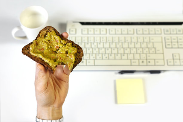 忙碌的商人一边忙着吃健康的牛油果吐司早餐，一边在电脑上工作图片下载