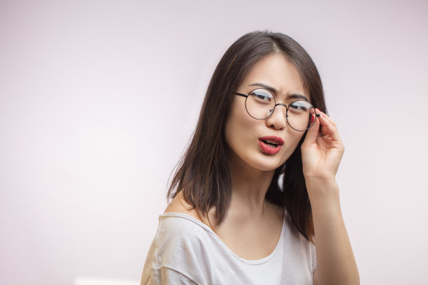 不满的亚洲女孩觉得眼睛疲劳调整眼镜在脸上。视力不佳。图片下载