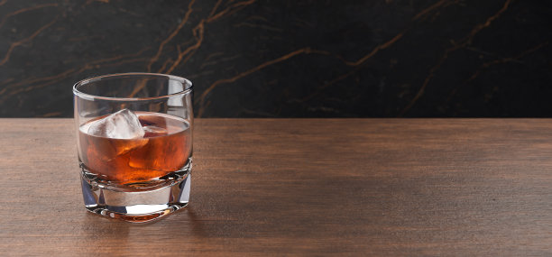 一杯加冰的苏格兰威士忌。威士忌，波旁威士忌，白兰地或朗姆酒放在木桌上。装有酒精饮料的杯子。图片下载