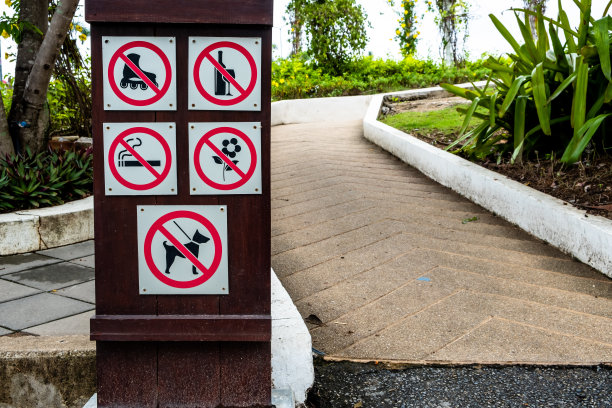 公园内的木版上以白色为背景的各种警告标志，例如禁止吸烟、禁止养宠物等。图片下载
