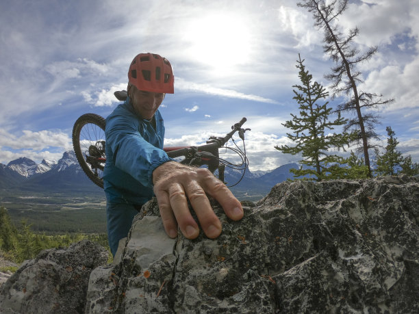山地摩托车手爬上山脊图片下载
