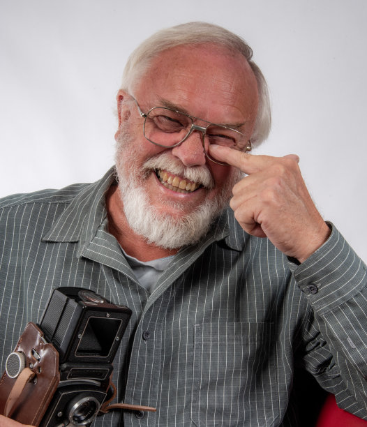 诙谐的照片，一个老人拿着旧相机，眼镜不见了。图片下载