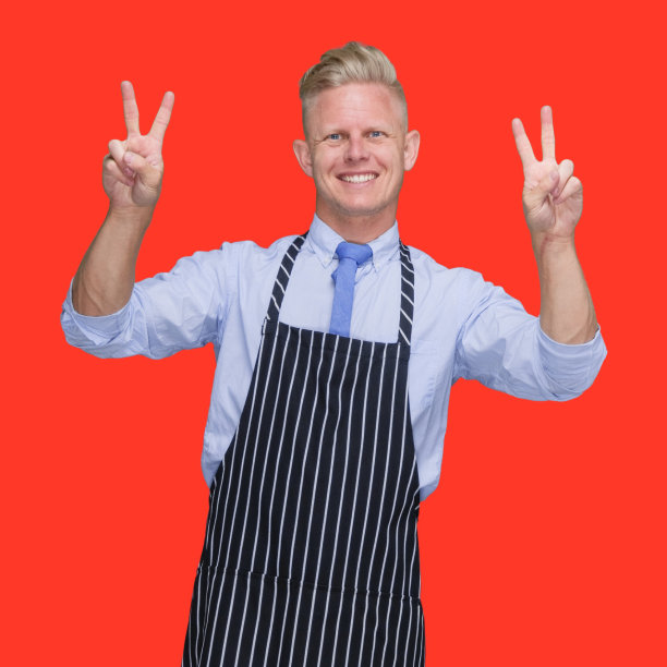 白人年轻男性屠夫穿着围裙站在黑色背景前图片下载