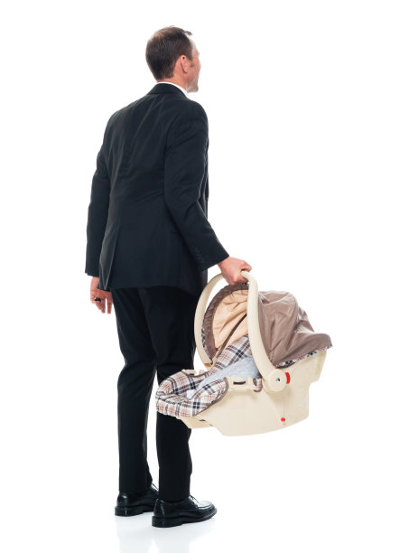 白种人婴儿-人类年龄站在白色背景穿着商务服装和持有汽车安全座椅图片下载