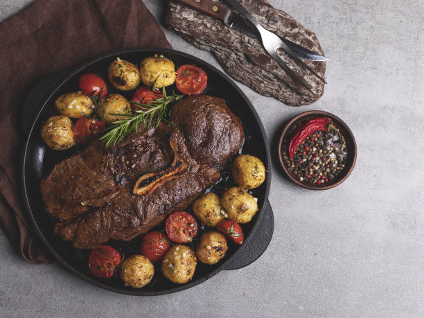 多汁的烤牛排配蔬菜，新鲜的土豆，番茄和大蒜图片下载