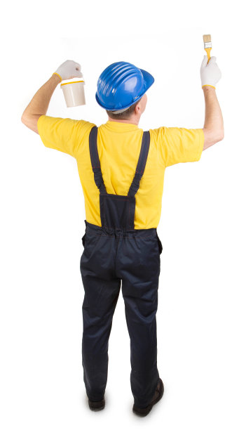 戴着头盔的工人拿着一把刷子和一桶油漆。图片下载