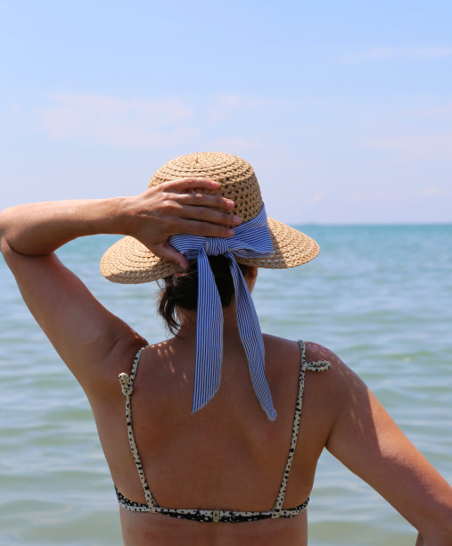 身材苗条的年轻女子戴着草帽望着大海图片下载