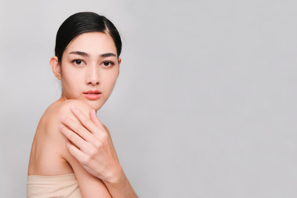 年轻美丽的亚洲女人干净新鲜的皮肤，手触摸脸颊，微笑和友好，面部护理，面部治疗，美容，美容和水疗，孤立在灰色的背景图片下载