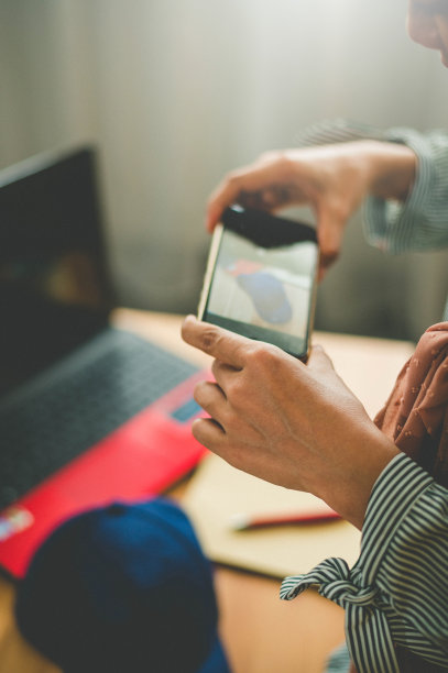 一名女性用智能手机拍下产品样品照片，然后寄给客户图片下载