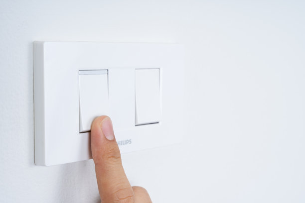 关闭手指打开或关闭白光开关与白色墙壁在家里。节能省电。为文本复制空间。图片下载