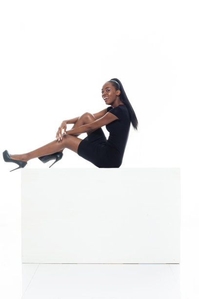 非洲裔女性坐在白色背景前穿着裙子和拿着盒子图片下载