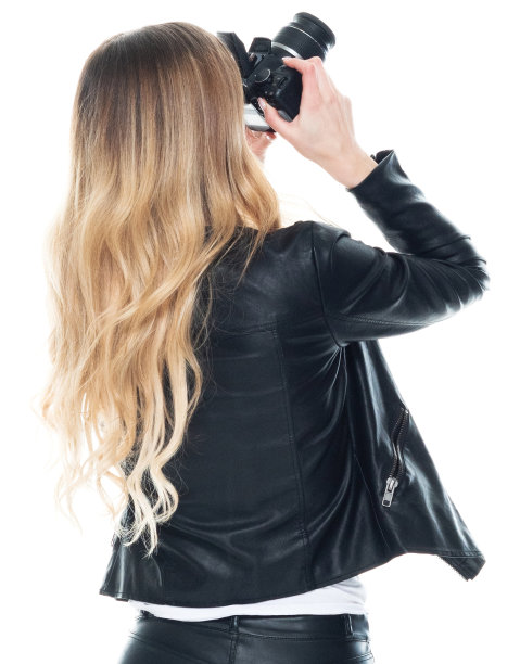 白人女摄影师穿着t恤，手持相机站在白色背景前图片下载