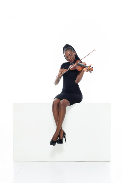 非裔美籍年轻女性在白色背景下演奏小提琴，穿着礼服，手持小提琴图片下载