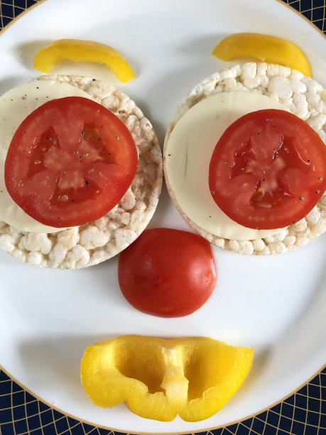 健康的米糕配上奶酪、番茄和黄色甜椒，健康的零食被做成笑脸，让孩子们看起来很有食欲。用糙米做成的年糕对身体有益，还有助于减肥图片下载