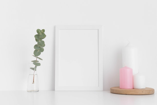 白色框架模型与蜡烛和桉树在花瓶上的白色桌子。肖像取向。图片下载