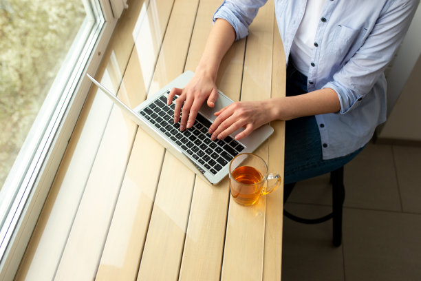 一位女士正在家里的笔记本电脑上打字图片下载