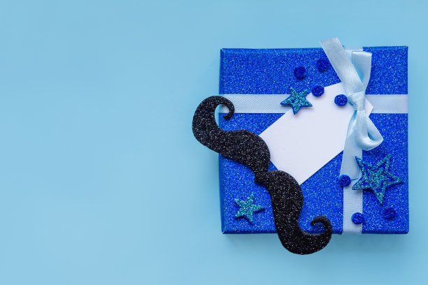 特写道具小胡子和礼物，许多小星星在蓝色背景下祝父亲节快乐。图片下载