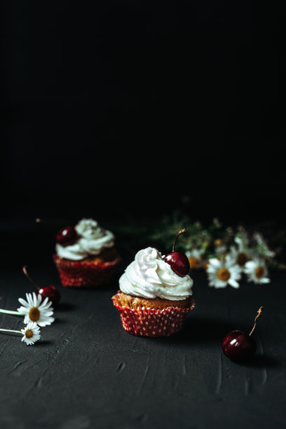 黑色背景上有奶油和樱桃的小蛋糕图片下载