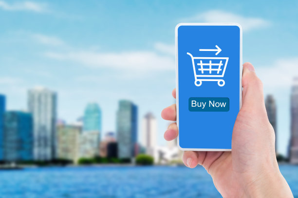 在商业大楼前，一个男子的手拿着手机进行网上购物的特写。图片下载