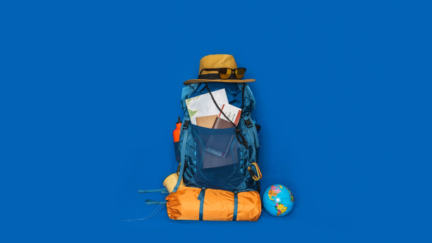 旅游规划假期与世界地图的帮助下，其他旅游配件周围。概念行李与配件的旅行者度假蓝色背景。旅行背包图片下载