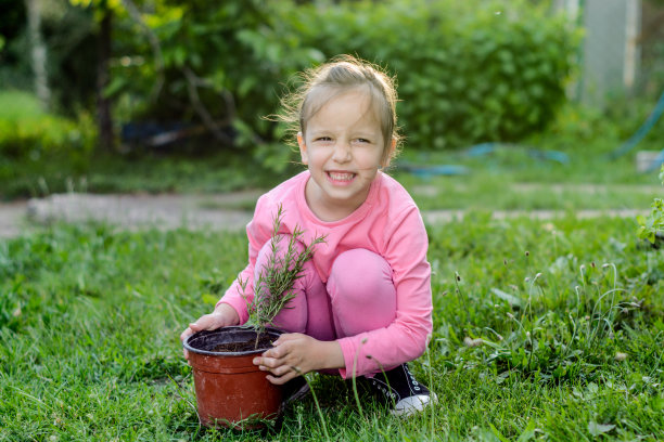 一个小女孩抱着院子里的植物图片下载