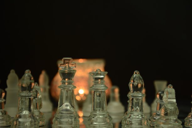 在黑色背景上分离的玻璃棋盘上的透明玻璃棋子图片下载