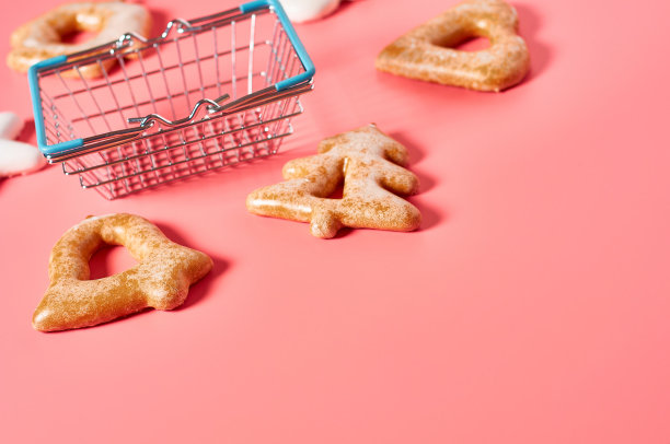 各种节日的圣诞饼干靠近空的市场篮子在粉红色的背景。新年庆祝概念图片下载