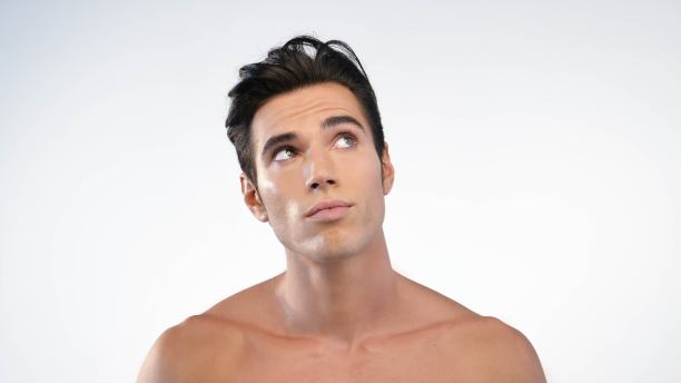 一个男人的特写与他的脸微笑的保湿，因为他的皮肤保湿和防止杂质与抗衰老的效果图片下载