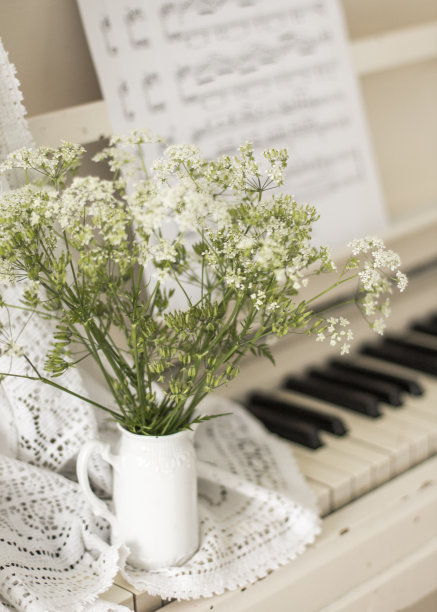 白色钢琴上放着一束野花，带着音符。复古的照片图片下载