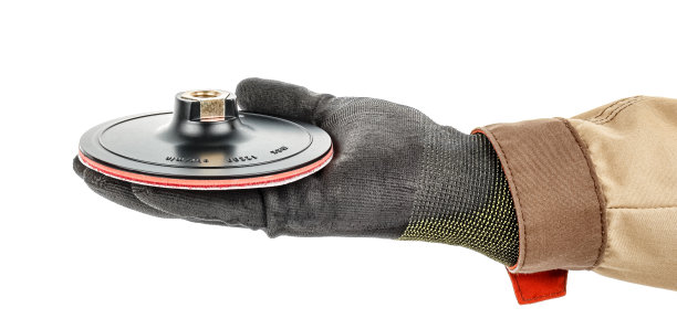 斜角磨床快拆座上的砂纸盘，戴着黑色防护手套，放在男手掌上，棕色均匀隔离在白色背景上图片下载