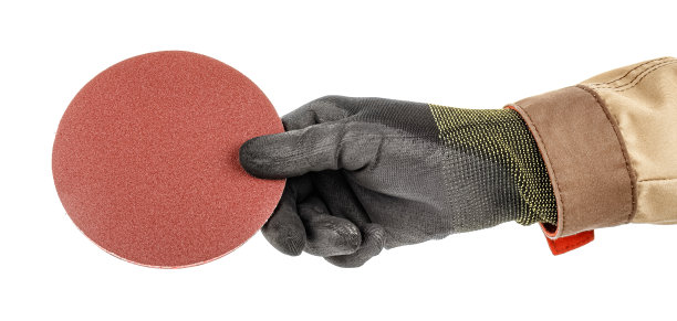 工人手戴黑色防护手套，在角磨机快拆架上打磨纸盘，棕色均匀隔离在白色背景上图片下载