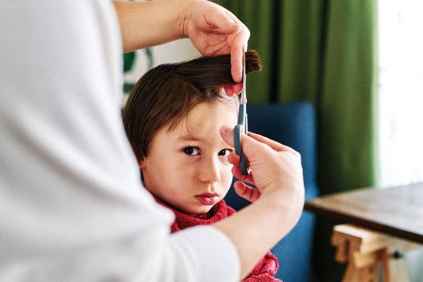 妈妈正在家里给儿子理发。图片下载