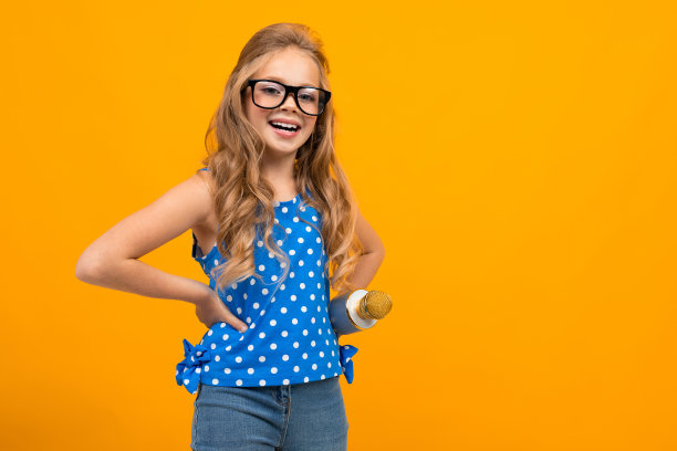 一个戴着眼镜拿着麦克风的小女孩被采访了，照片被孤立在黄色的背景上图片下载