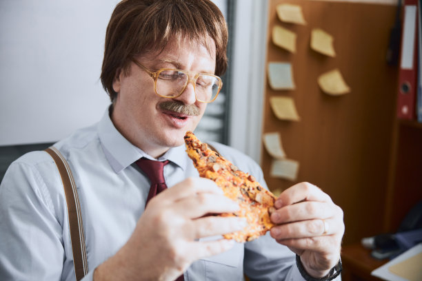 饥饿的老职员手里拿着一片披萨图片下载