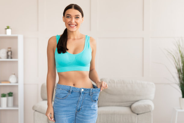 快乐女孩在家瘦身后穿着太大的牛仔裤图片下载