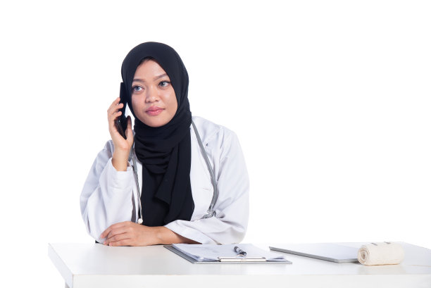一个愉快的女穆斯林医生在用智能手机图片下载