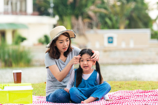 母亲们用发卡把头发系在女儿身上。女人用发束。在花园里的家庭野餐。图片下载