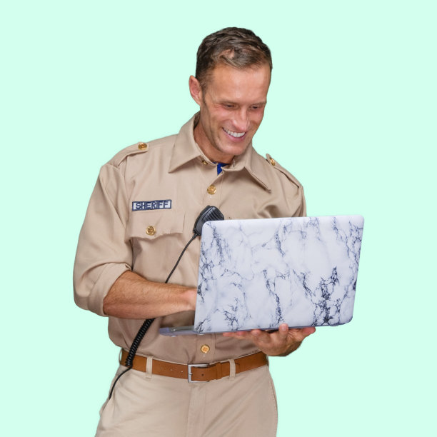 白人男性警察站在有色背景下佩戴警徽并使用电脑图片下载