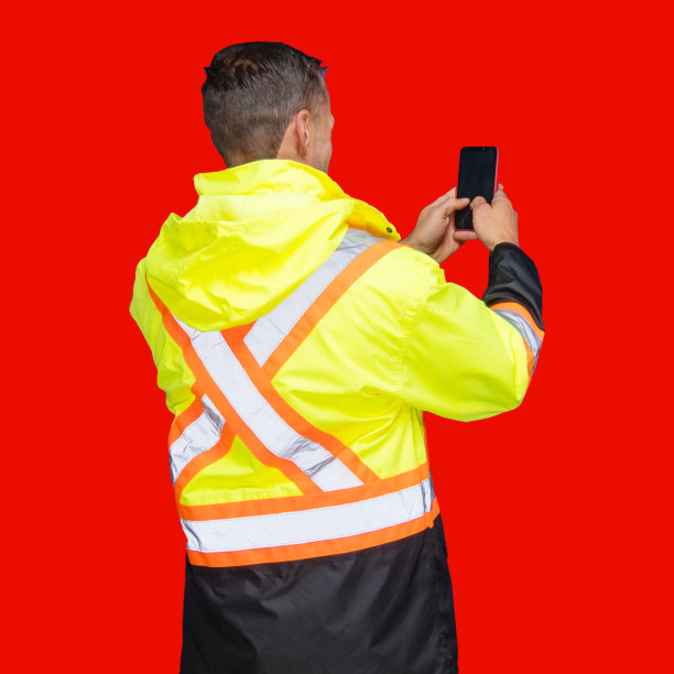 一名男性建筑承包商穿着反光服站在彩色背景前发短信图片下载