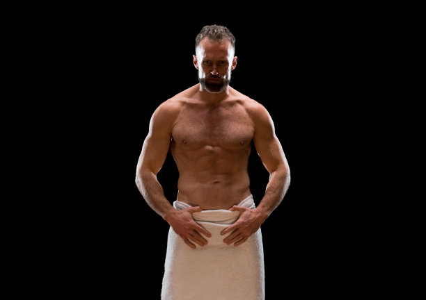 白人年轻男性穿着毛巾站在黑色背景前图片下载