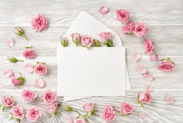 空白信封，玫瑰花在木制背景。俯视图粉色玫瑰和玫瑰花蕾。快乐的母亲节。图片下载