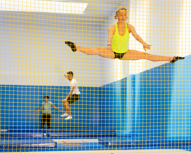 女子体操运动员在蹦床上跳跃图片下载