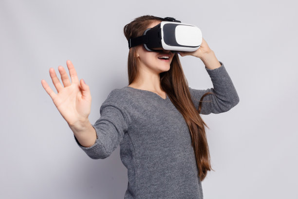戴着虚拟现实眼镜的女人。工作室拍摄，灰色背景图片下载
