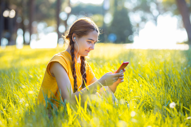 年轻女子在草地上听着电话音乐图片下载
