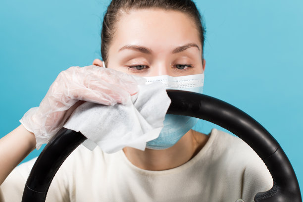 女孩小心地给方向盘消毒。孤立在蓝色背景上图片下载