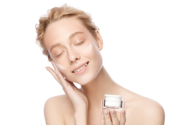 女性美容治疗理念。年轻微笑美丽的女人皮肤拿化妆品罐和涂抹霜的脸，孤立在白色的背景图片下载