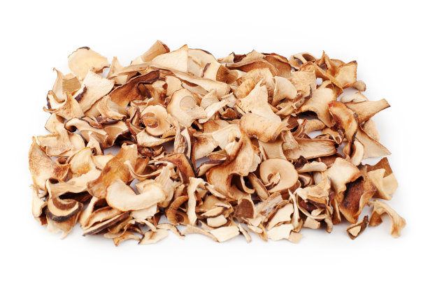 可食用的干蘑菇堆在白色的背景近处，干牛肝菌堆，切成棕色的牛肝菌帽，切成薄片的小圆面包，羊肝菌片，牛肝菌或牛肝菌，切成白色的真菌纹理俯视图图片下载