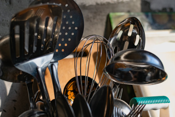 白色的架子上放着金属餐具。厨房里放着银勺、叉子和不锈钢刮刀，图片下载