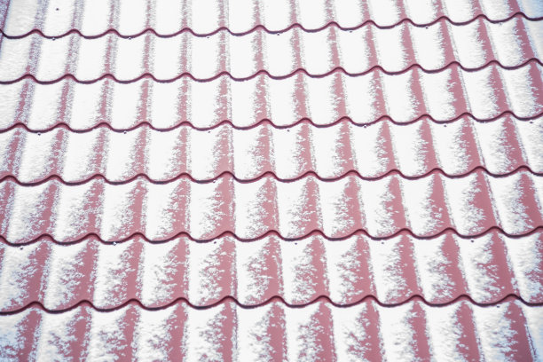 纹理特写红色金属屋顶瓦覆盖了一层薄薄的雪。软焦点图片下载